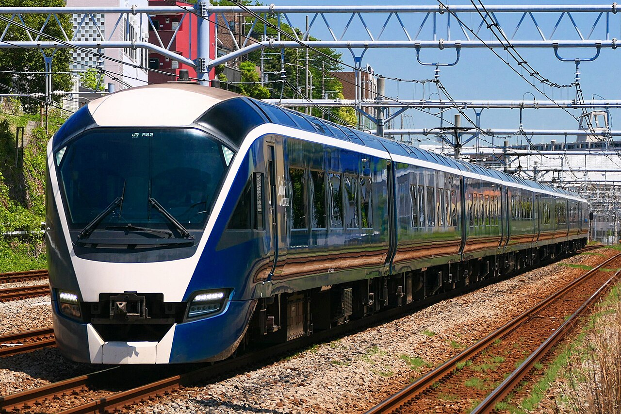 Blue-and-white Saphir Odoriko panoramic train under overhead wires in Japan