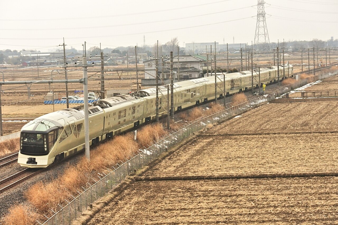 Champagne-gold Train Suite Shiki-shima traveling through open farmland in Japan